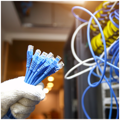Uma pessoa segurando com luva diversos cabos de rede em frente a um data center